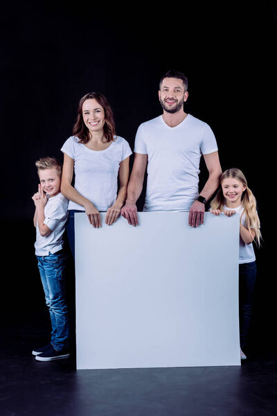 Smiling family holding blank card