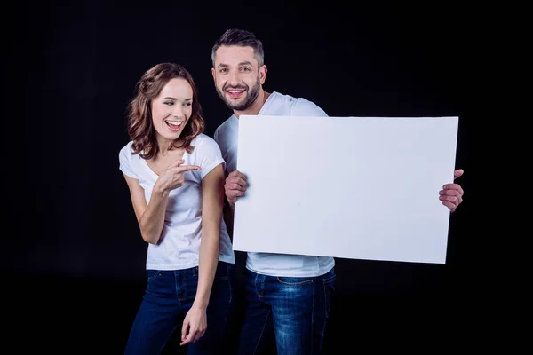 Pareja sonriente sosteniendo tarjeta en blanco — Foto de Stock