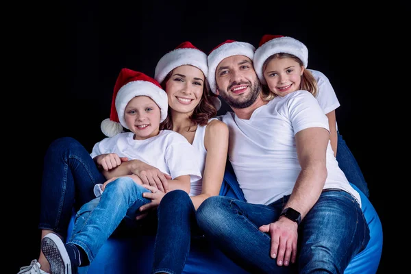 Familie mit Weihnachtsmannhüten blickt in die Kamera — kostenloses Stockfoto