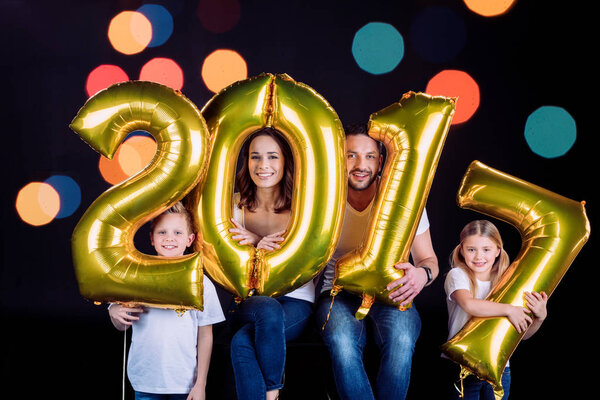 Happy family holding golden balloons 