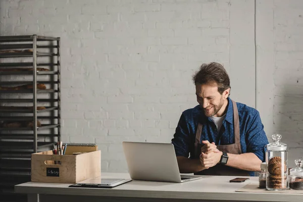 Man working with laptop at bakery — Stock Photo, Image