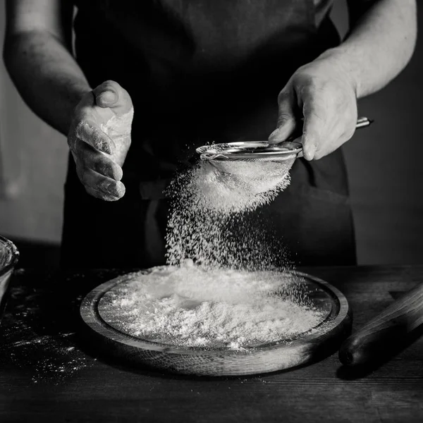 Baker peneirando farinha — Fotografia de Stock