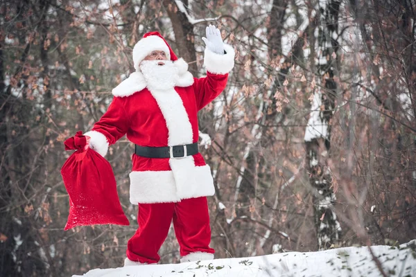 Père Noël marche avec un sac plein de cadeaux — Photo de stock