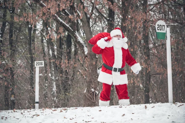 Santa Claus caminando con saco en la espalda - foto de stock