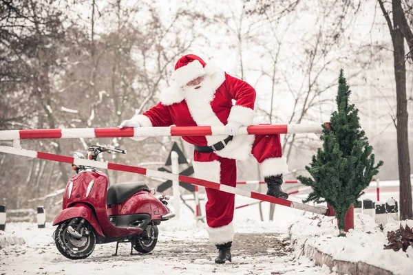 Santa Claus climbing over barrier — Stock Photo