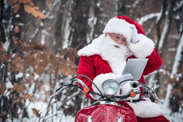 Santa Claus on scooter using tablet — Stock Photo