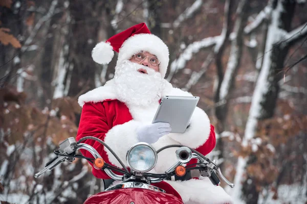 Papai Noel em scooter usando tablet — Fotografia de Stock