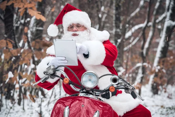 Santa Claus on scooter using tablet — Stock Photo