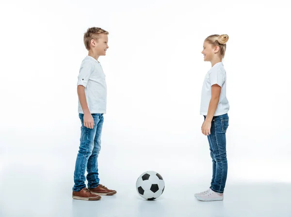 Братья и сестры, стоящие с футбольным мячом — стоковое фото