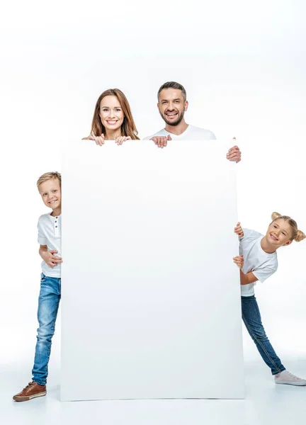 Famille souriante tenant une carte blanche — Photo de stock