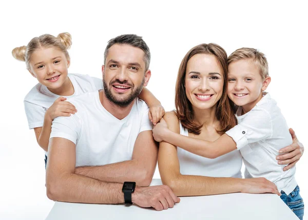 Familia sonriente en camisetas blancas abrazándose - foto de stock