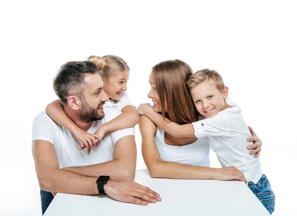 Família sorridente em camisetas brancas abraçando — Fotografia de Stock