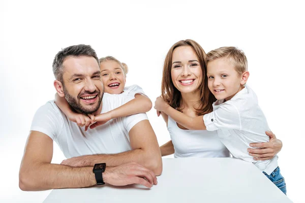 Familia sonriente en camisetas blancas abrazándose - foto de stock