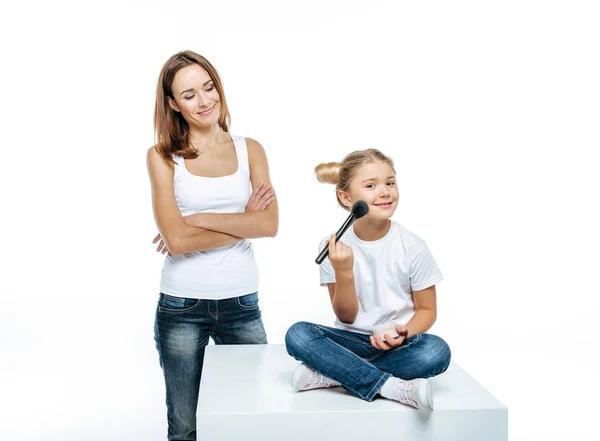 Mother looking at daughter with makeup brush — Stock Photo