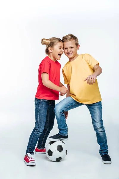 Frères et sœurs debout avec un ballon de football — Photo de stock