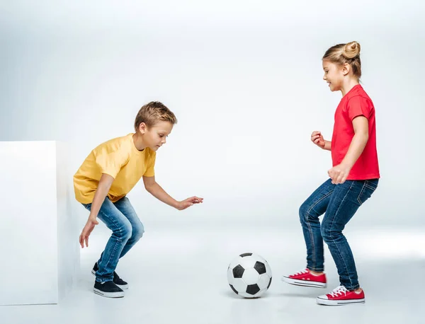 Frères et sœurs jouant avec le ballon de football — Photo de stock