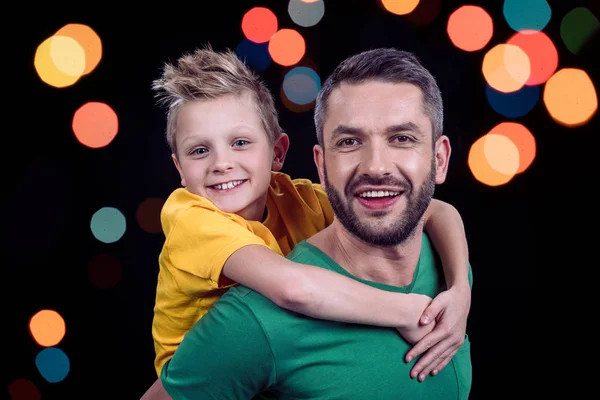 Padre piggybacking feliz niño - foto de stock