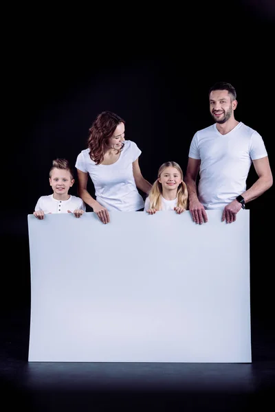 Família de pé com cartão branco em branco — Fotografia de Stock