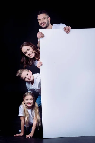 Familia feliz sosteniendo tarjeta en blanco - foto de stock