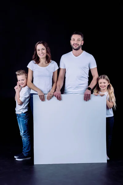 Família sorridente segurando cartão em branco — Fotografia de Stock