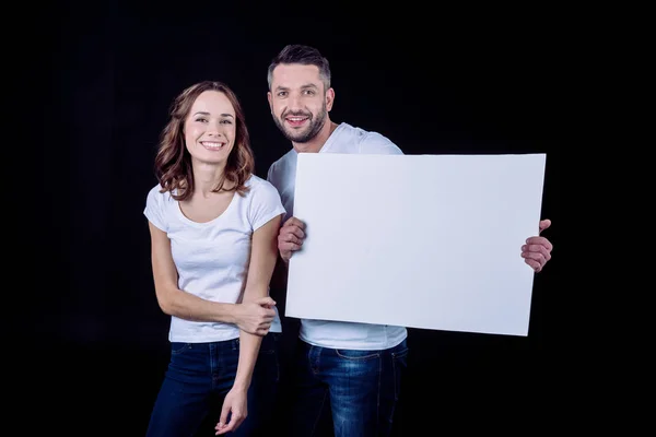 Smiling couple holding blank card — Stock Photo