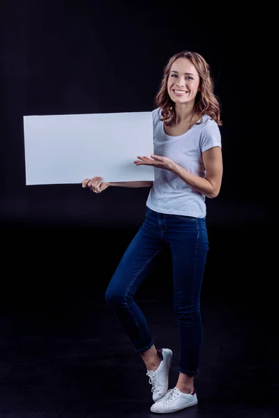 Femme souriante tenant une carte blanche — Photo de stock