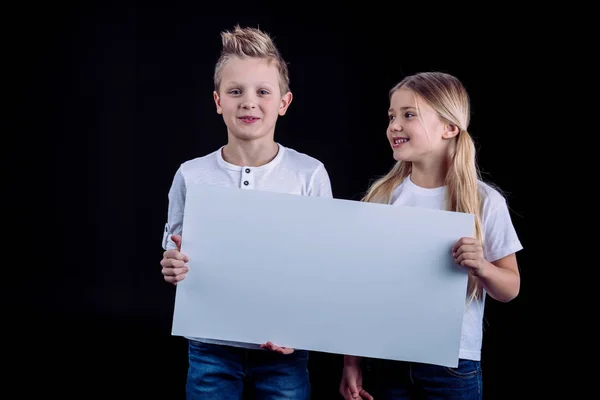 Lächelnde Geschwister mit leerer Karte — Stockfoto