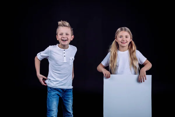 Hermanos sonrientes con tarjeta en blanco - foto de stock