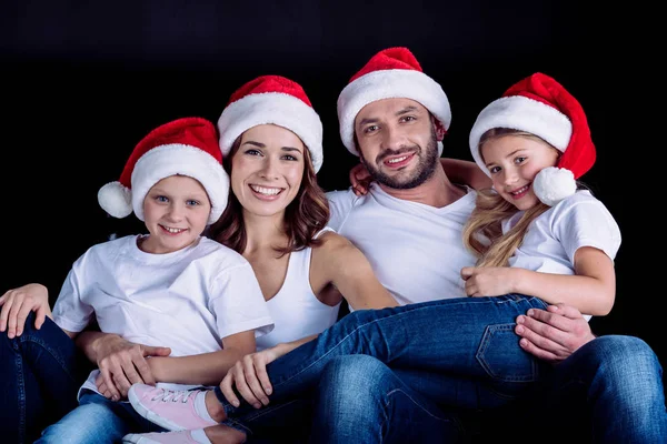 Famille dans Santa chapeaux regardant caméra — Photo de stock