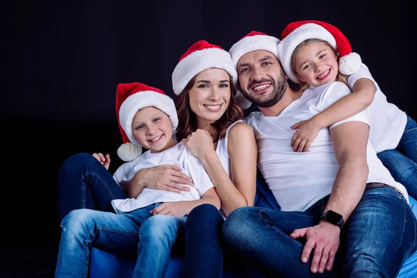 Familia en Santa sombreros mirando a la cámara - foto de stock