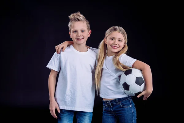 Hermano y hermana posando con pelota de fútbol - foto de stock