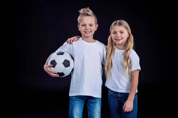 Brother and sister posing with soccer ball — Stock Photo