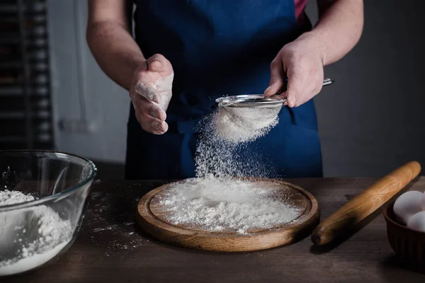 Baker peneirando farinha — Fotografia de Stock