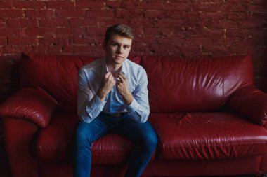 kot pantolon ve gömlek genç bir adam kanepede oturuyor.