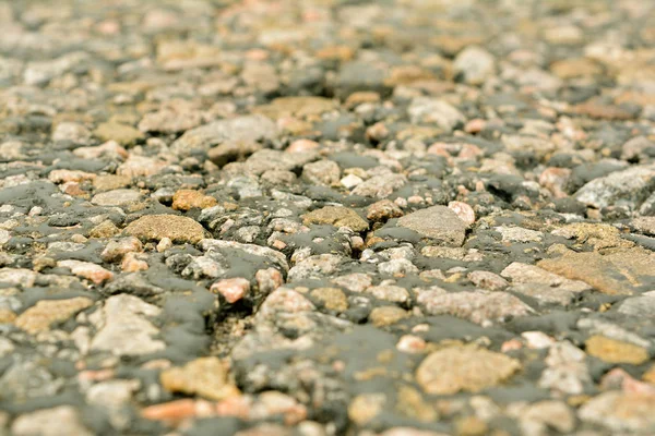 La vieille route, de petites pierres et de l'asphalte se rapprochent avec une petite roche — Photo