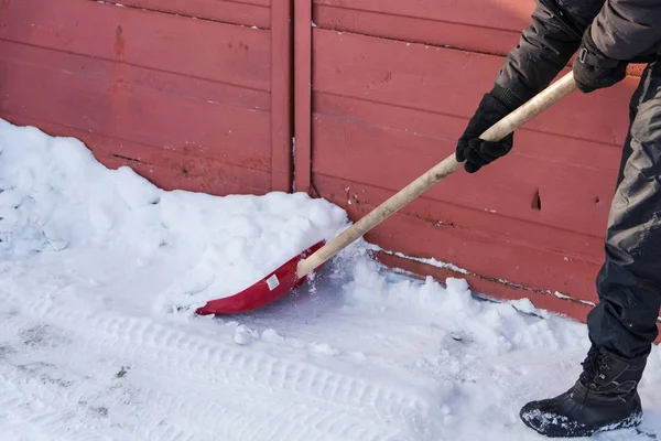 De persoon gooit een rode schop sneeuw. — Stockfoto