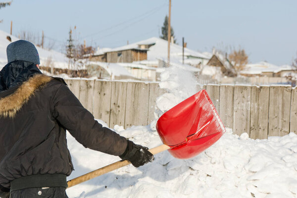 The person throws a red shovel snow.