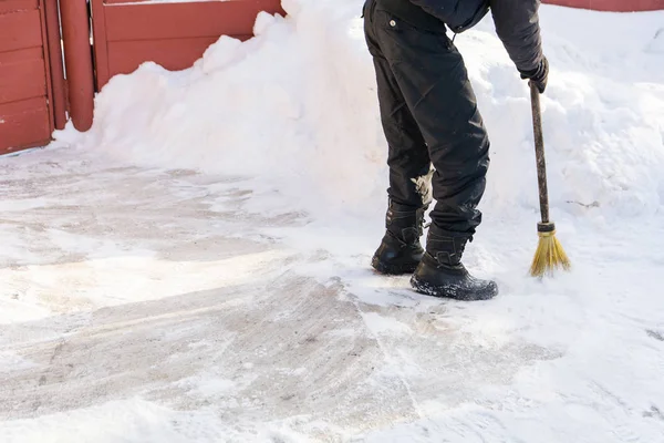 De persoon veegt met de bezem sneeuw. — Stockfoto