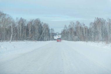 Araba kış yolunda gidiyormuş. Karlı yol. Kış ormanının içinden geçen yol. Kırmızı araba yolda..