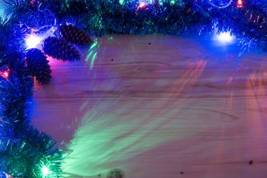 Noel arkaplanı. Ahşap bir arka planda çelenk parıldıyor. Renkli Noel ışıkları arka planı