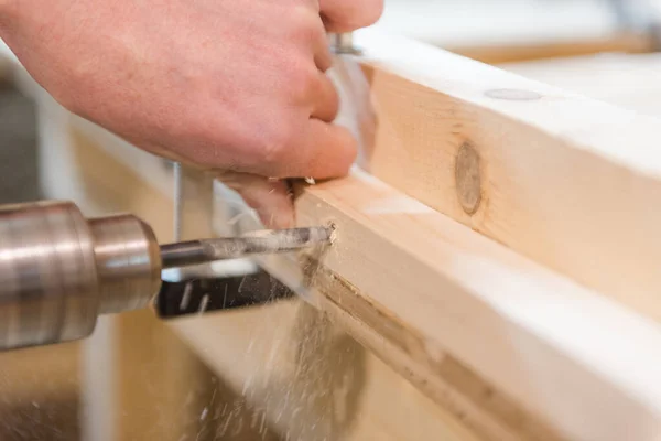 drill a hole with a drill. man drills a hole in the board.