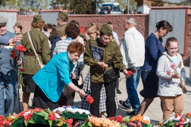 Zarinsk, Rusya - 9 Mayıs 2019: Zafer Günü 'nde insanlar çiçek bırakır. Çiçekleri 9 Mayıs 'ın ebedi ateşine seriyorum..