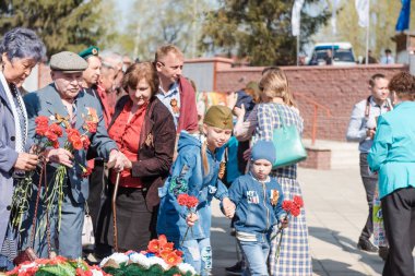 Zarinsk, Rusya - 9 Mayıs 2019: Zafer Günü 'nde insanlar çiçek bırakır. Çiçekleri 9 Mayıs 'ın ebedi ateşine seriyorum..