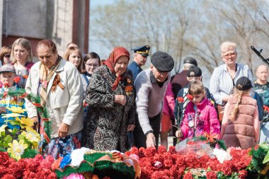 Zarinsk, Rusya - 9 Mayıs 2019: Zafer Günü 'nde insanlar çiçek bırakır. Çiçekleri 9 Mayıs 'ın ebedi ateşine seriyorum..