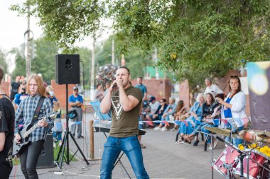 Zarinsk, Rusya - 19 Ağustos 2019: Gençler şarkı söyler. Parktaki meydanda şarkı söylemek. Sokaktaki rock konseri