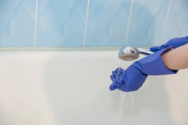 The girl cleans the bath, the water in the shower, clean the bath, the girl cleans the white bath, with rubber glove — Stock Photo, Image