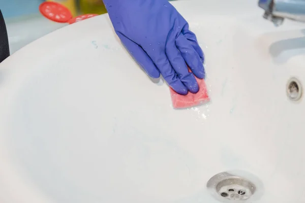 The girl cleans the bathroom, clean the ceramic sink in the bathroom, wash with rubber gloves, clean up the house — Stock Photo, Image