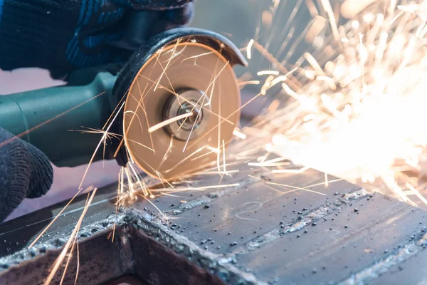 Metallo tagliato con una rettificatrice angolare. Sparks stanno volando. Strumento di costruzione smerigliatrice. Un uomo sta tagliando il metallo. Indossare guanti per la sicurezza . — Foto Stock