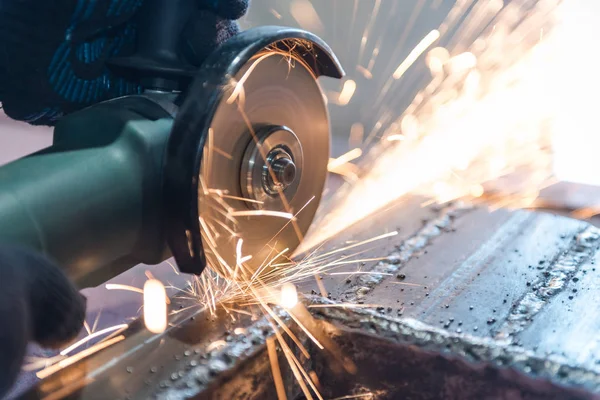 Cut metal with a Angular grinding machine. Sparks are flying. Construction tool grinder. A man is cutting metal. Wear gloves for safety. — Stock Photo, Image