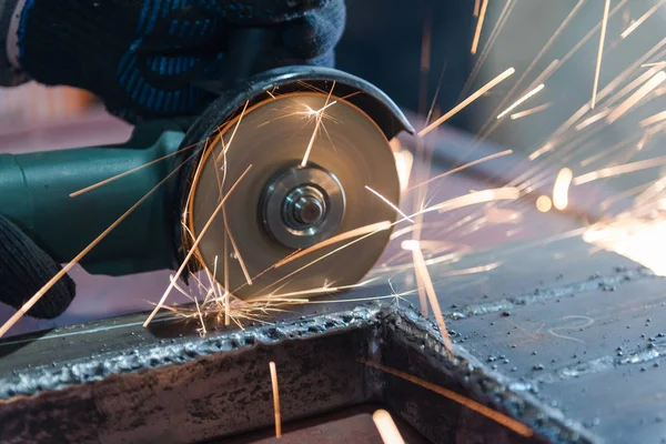 Metallo tagliato con una rettificatrice angolare. Sparks stanno volando. Strumento di costruzione smerigliatrice. Un uomo sta tagliando il metallo. Indossare guanti per la sicurezza . — Foto Stock